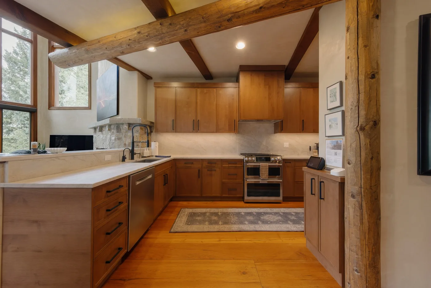 Una cocina de tonos cálidos con armarios de madera, una isla central y vigas expuestas.
