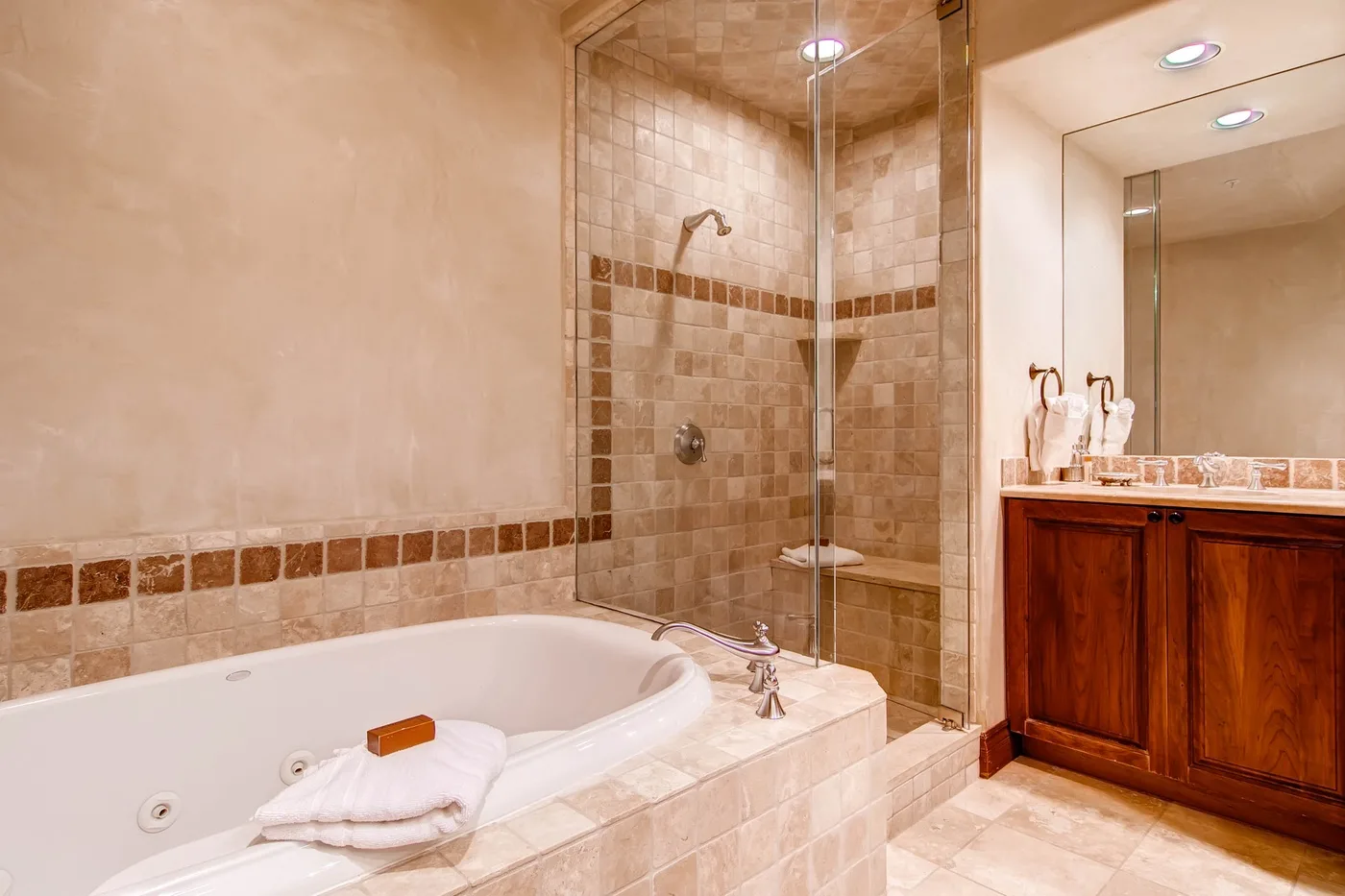 Un baño cuenta con una bañera empotrada, una ducha alicatada y un tocador de madera.
