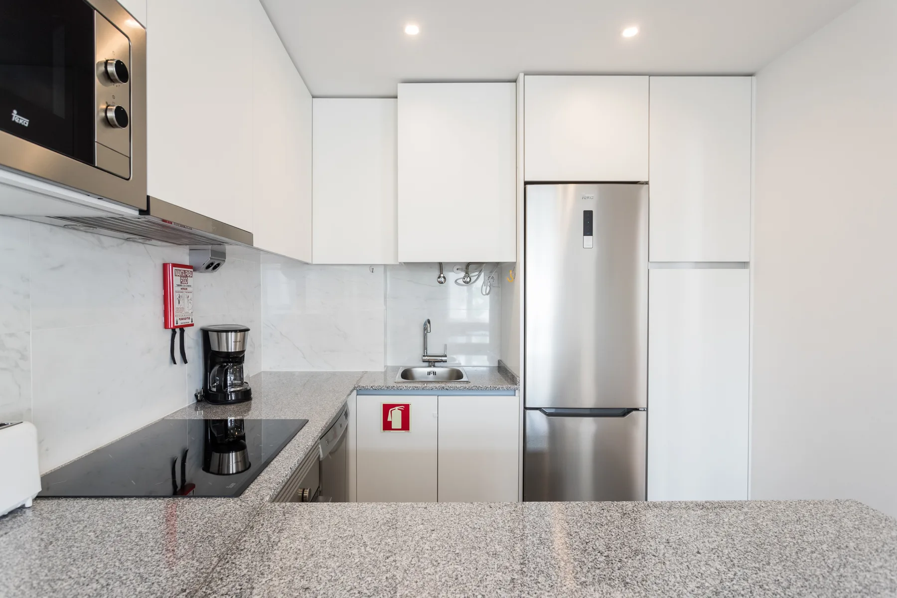 A modern kitchen with white cabinets, a countertop, and stainless steel appliances.