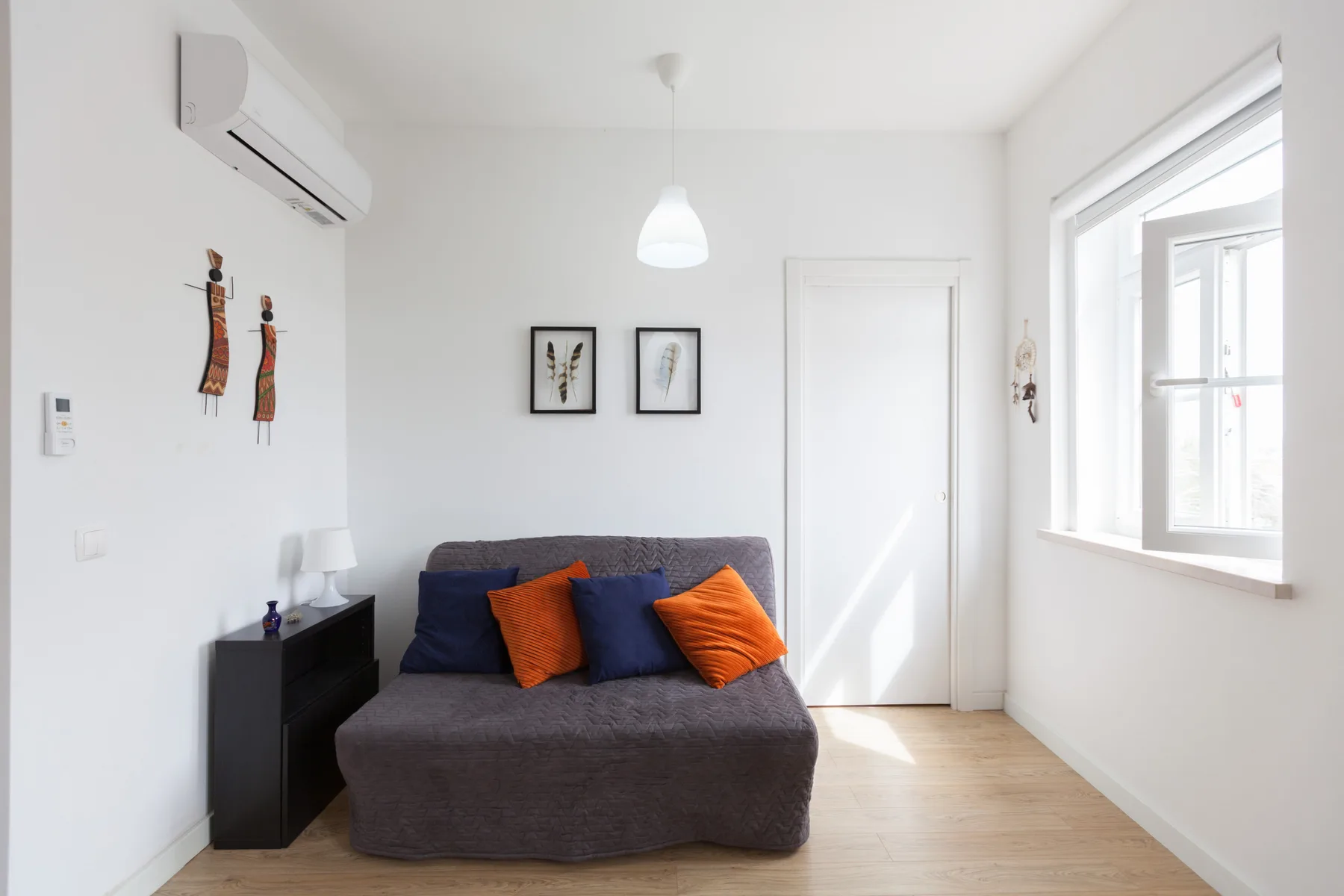 A bright living room with a dark sofa beneath two framed prints.