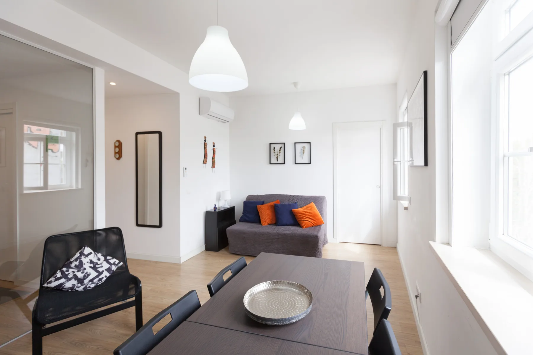 A bright living and dining area with seating, a table, and large windows.