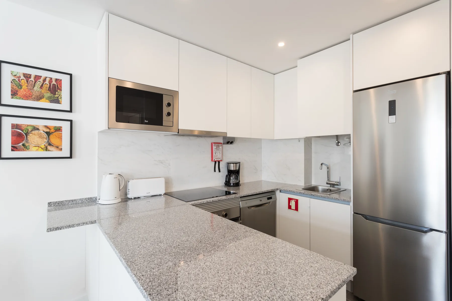 A bright kitchen with white cabinets, stainless steel appliances, and a large countertop.