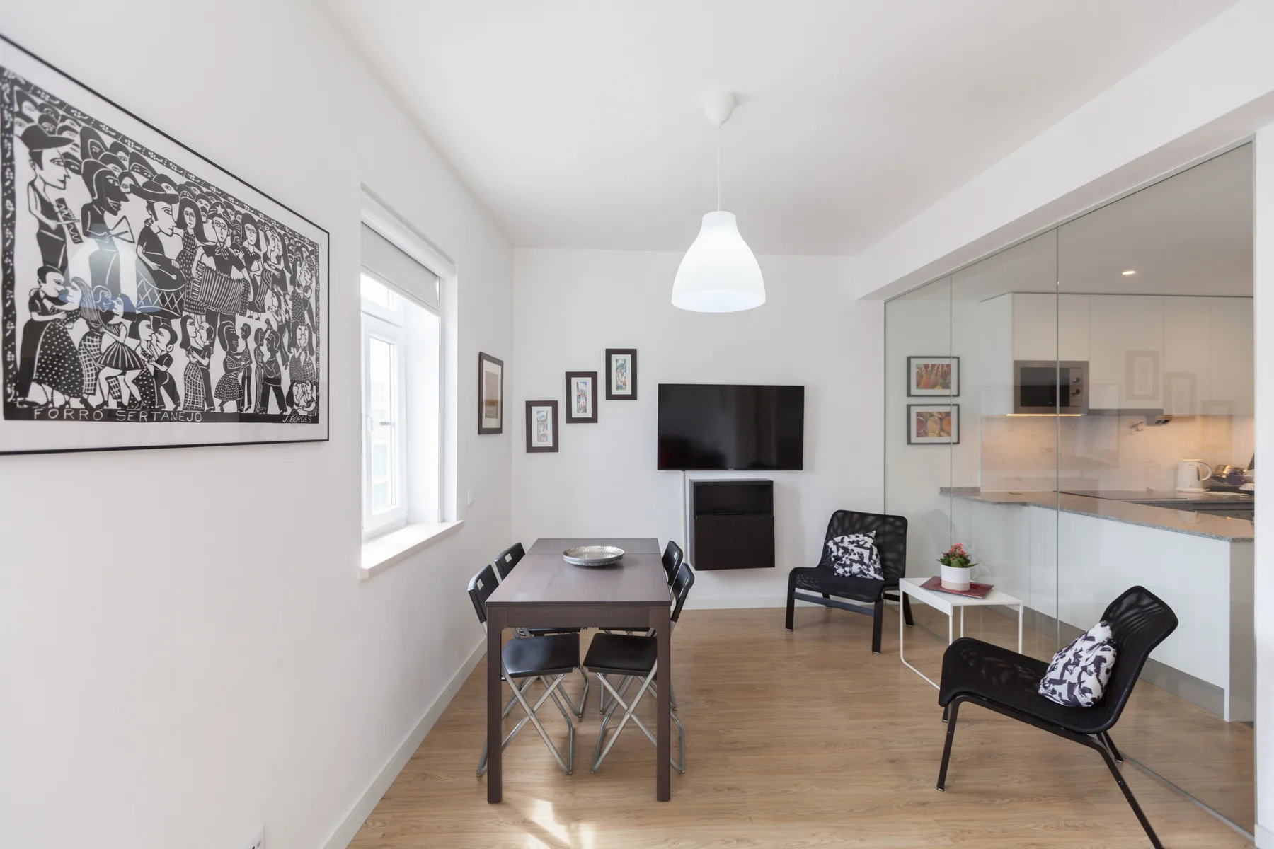 A dining and living area with a table, seating, and a wall-mounted television.