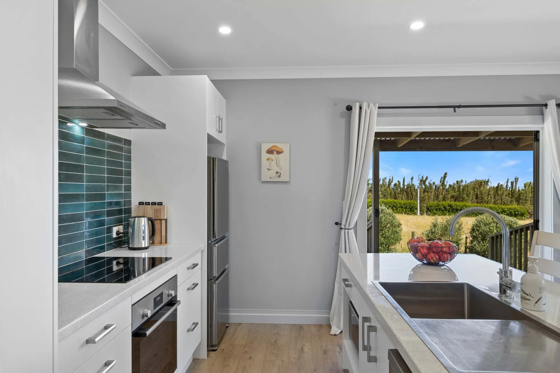 Una cocina luminosa con un salpicadero de azulejos oscuros y vista a través de puertas abiertas.