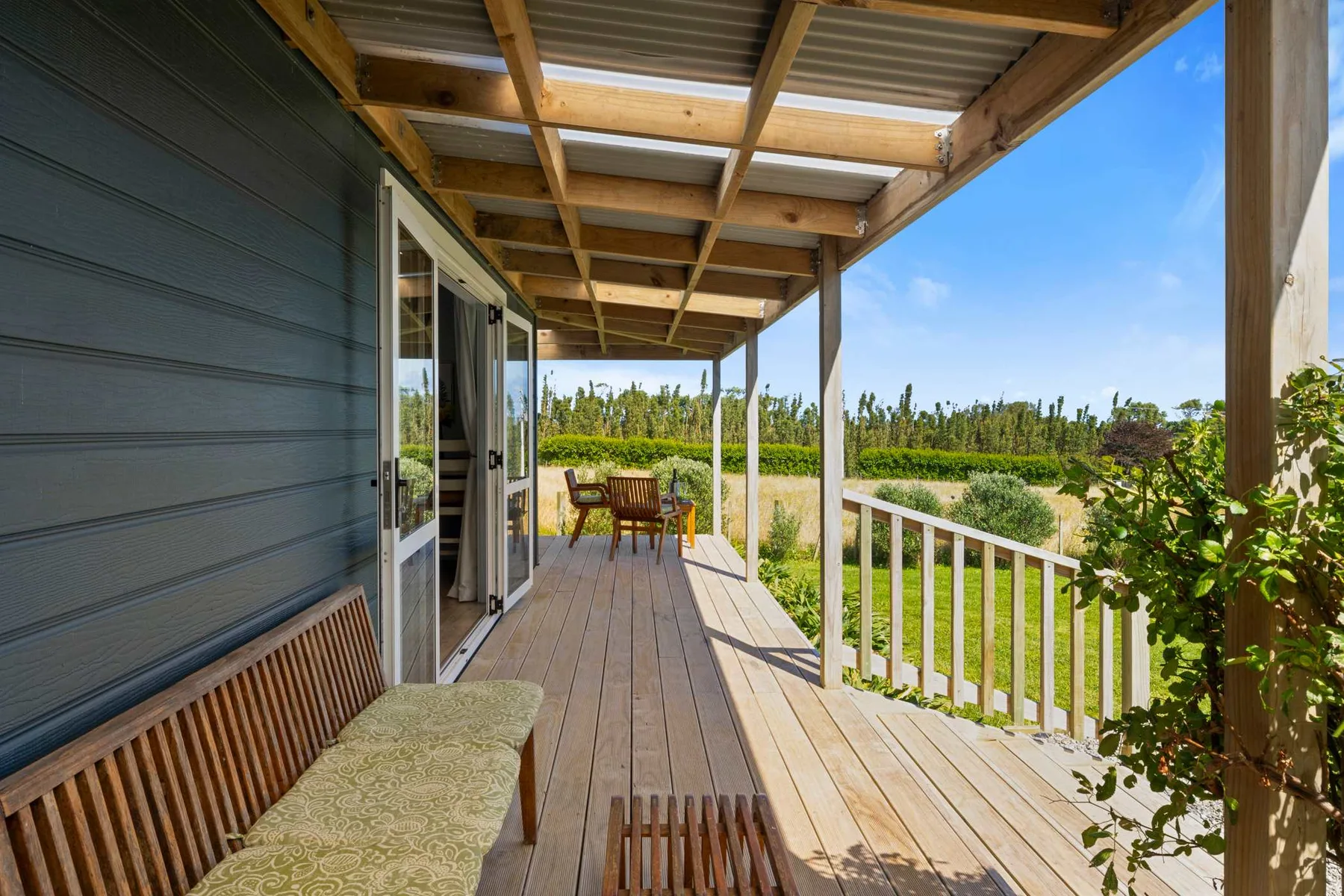 Una terraza exterior cubierta con asientos de madera y vistas a un paisaje verde.