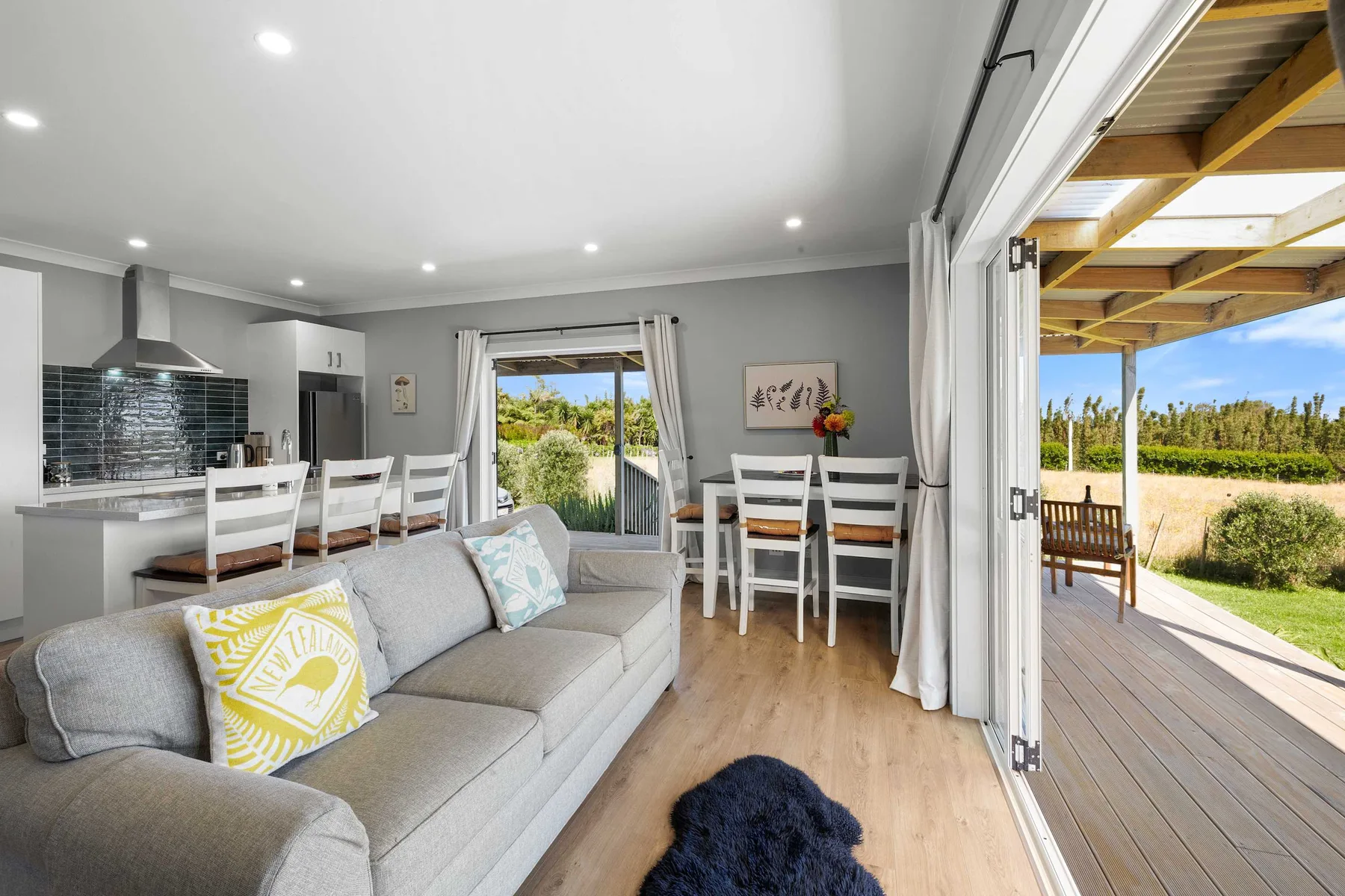 An open-plan living and dining area with a kitchen and doors opening onto a covered deck.