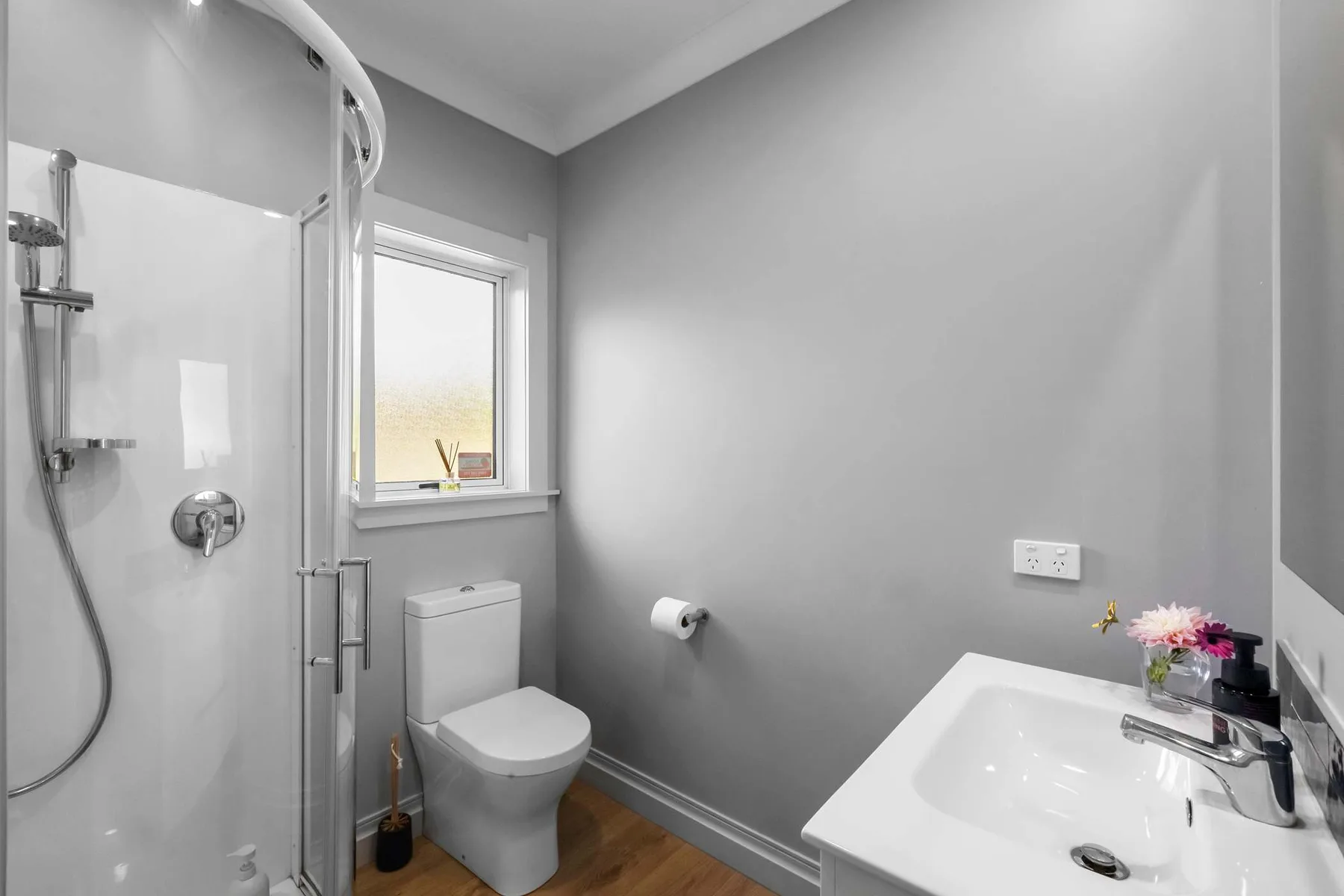 A bathroom with a glass shower, toilet, and sink.