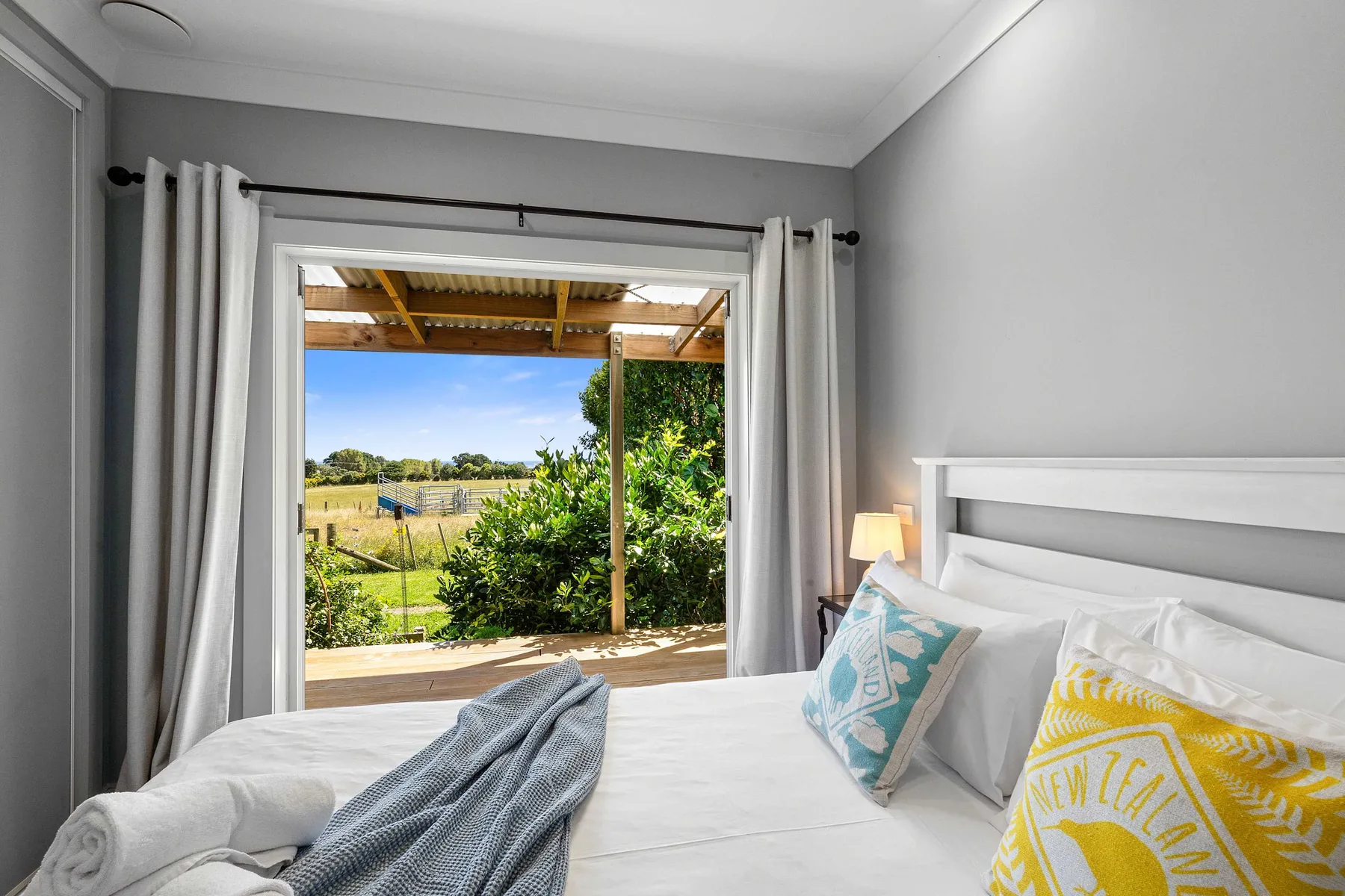 A bedroom opens onto a covered patio with a view of greenery.