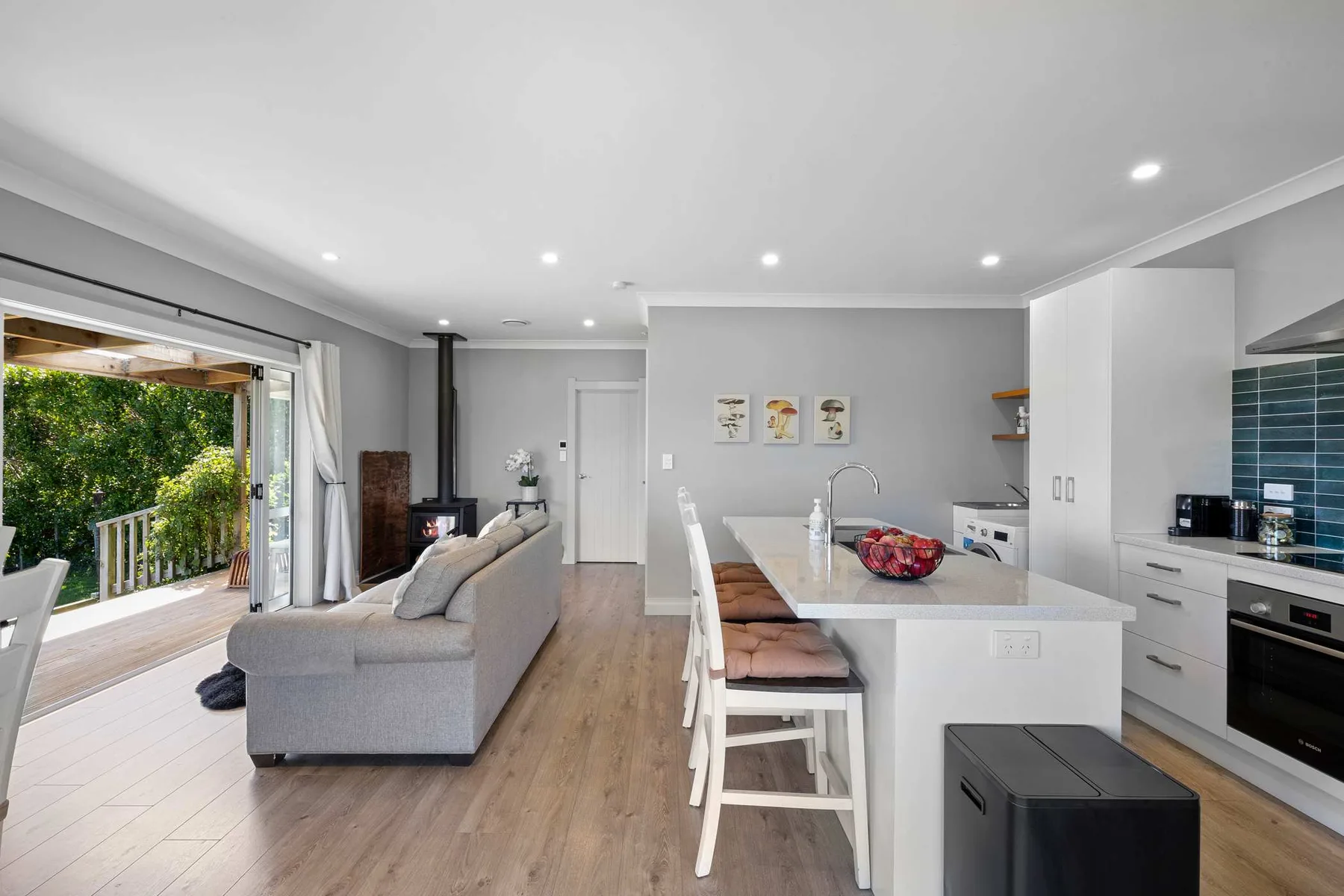 An open-plan living room and kitchen with a dining island and sliding doors to a patio.