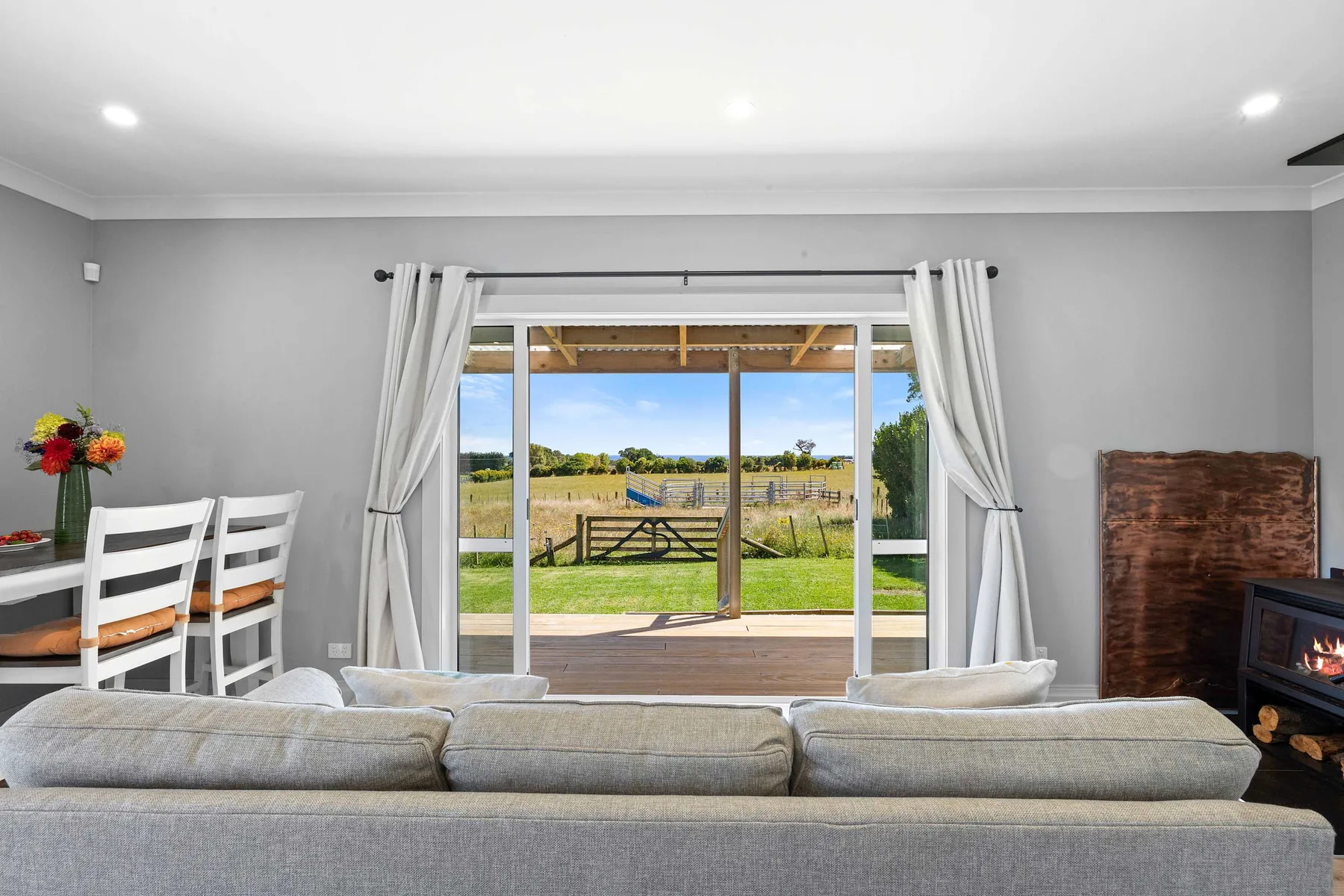 Living room with seating facing open sliding doors and a view of a grassy field.