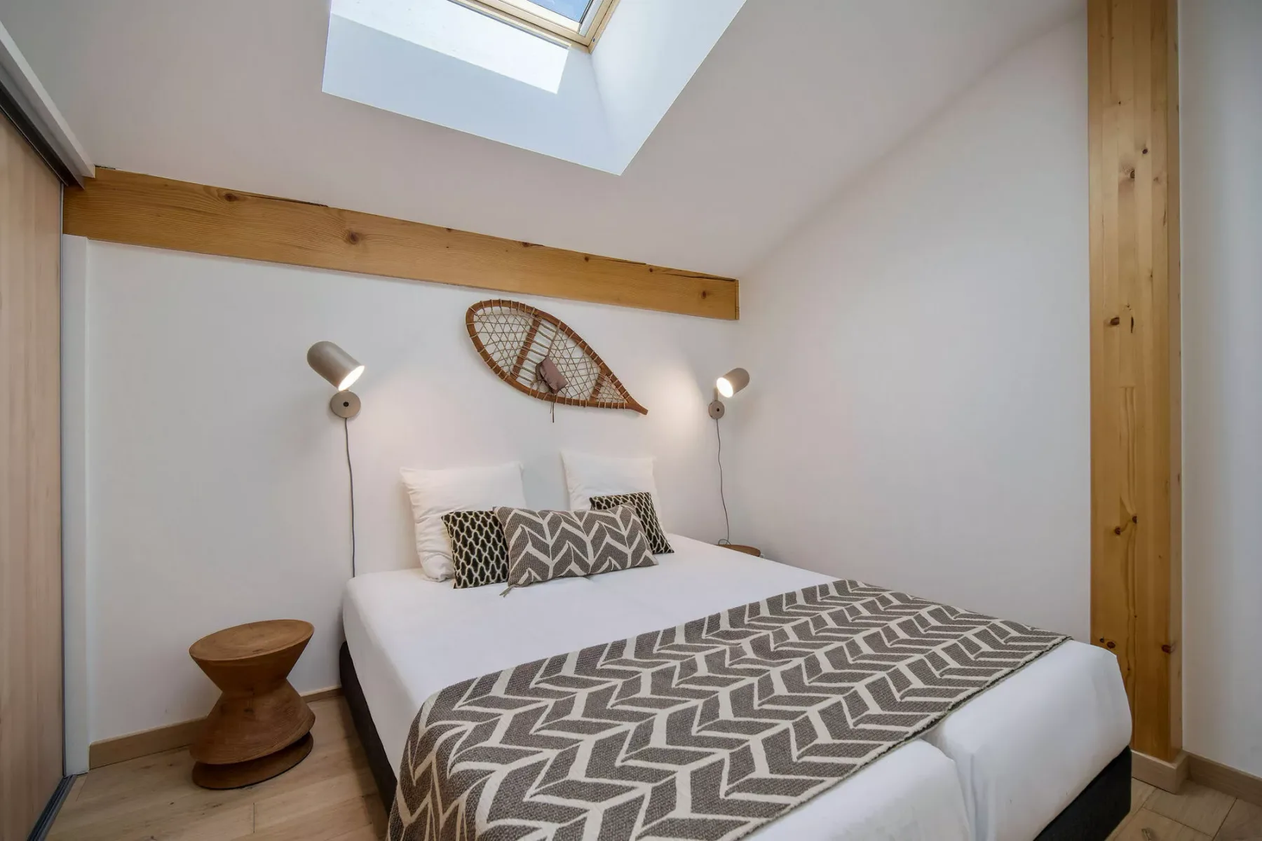 Un dormitorio con cama doble, ropa de cama estampada y una claraboya.