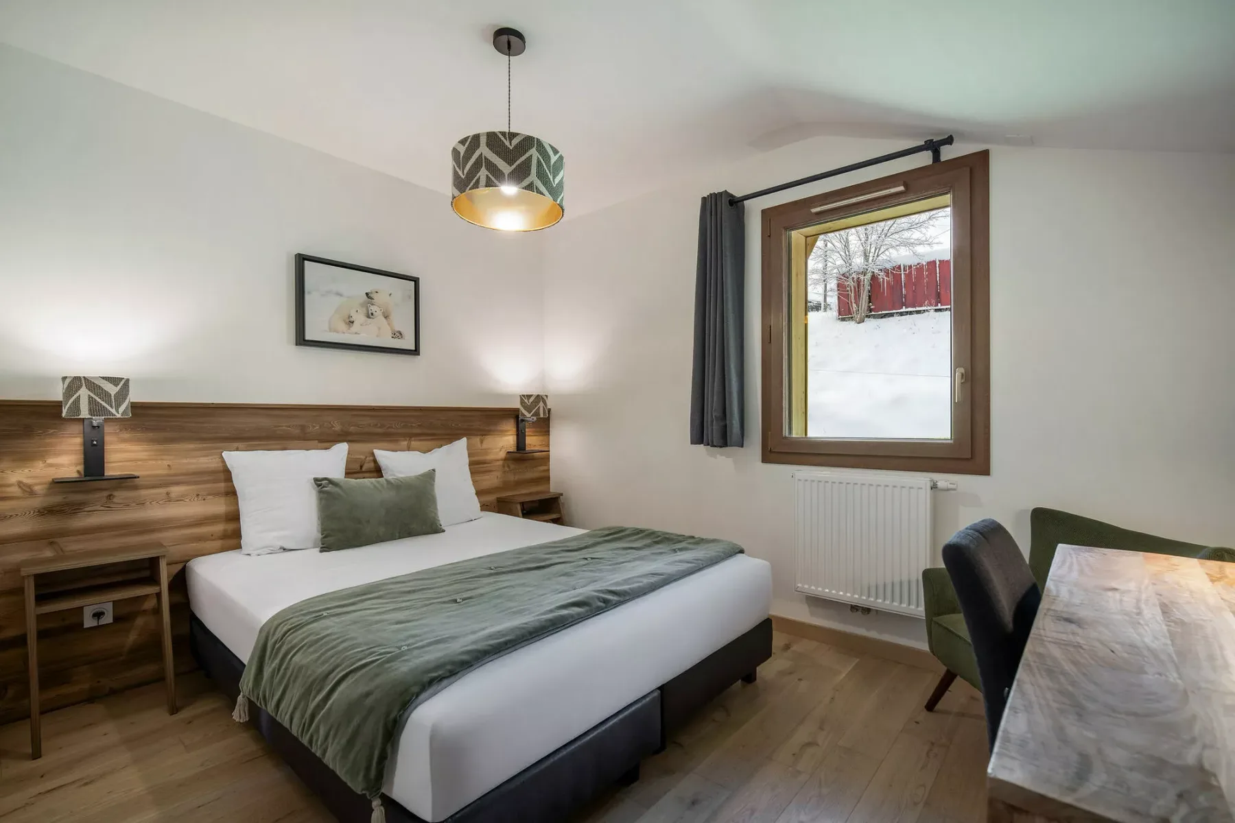 Un dormitorio con cama doble, lámparas de noche y una ventana con vistas a la nieve.