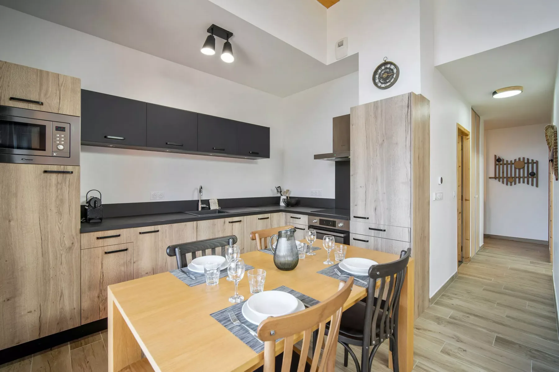 A kitchen and dining area with a set table and light wood cabinetry.