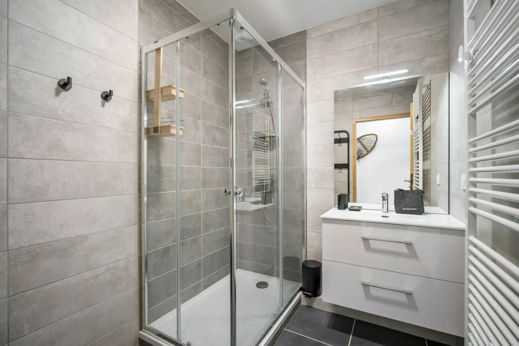 Un baño con azulejos, una ducha de vidrio y un tocador con espejo.