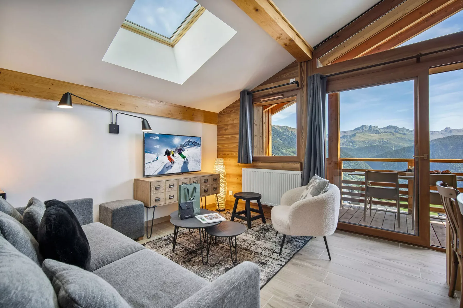 A bright living room with seating and large windows overlooking a mountain landscape.