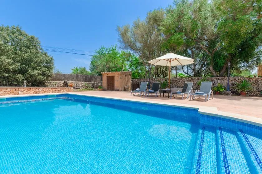 An outdoor swimming pool with lounge seating and an umbrella beside it.