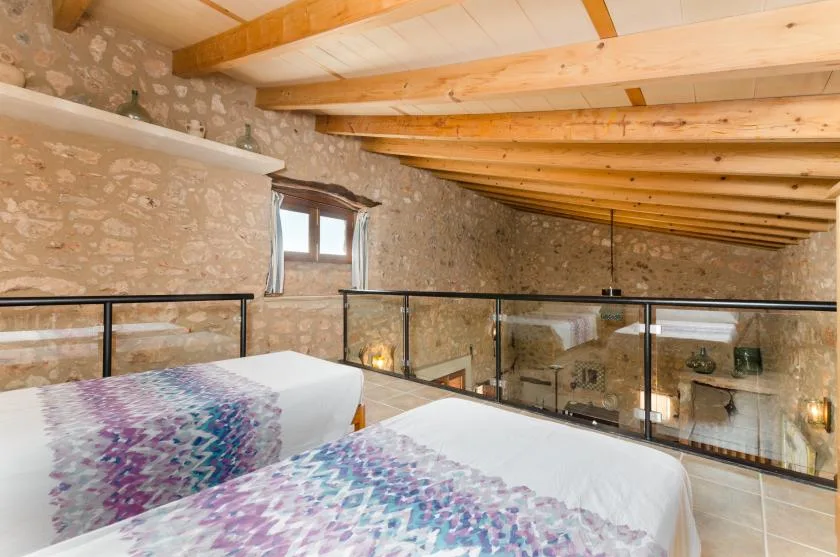 A sleeping area with two beds beneath exposed wooden ceiling beams.