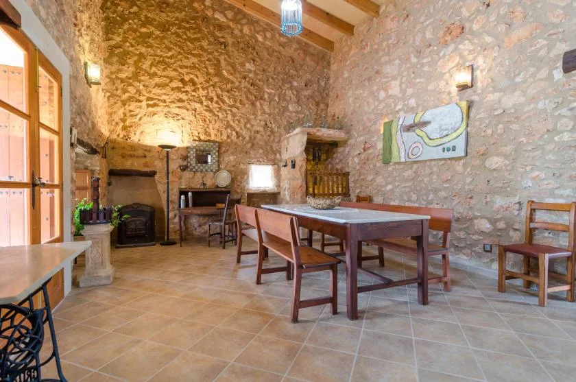 A rustic stone dining room with a long wooden table and chairs.