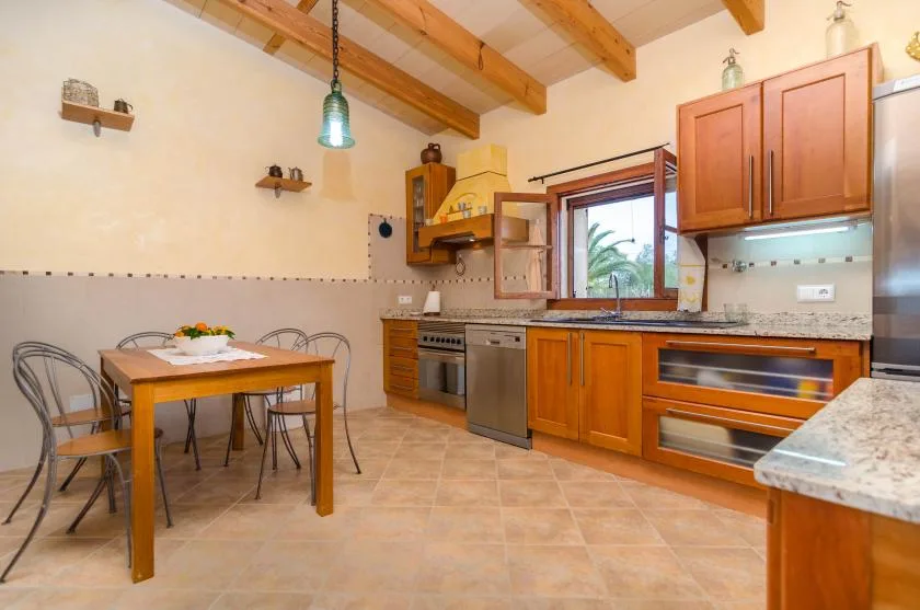 A kitchen and dining area with wooden cabinets, a table, and exposed ceiling beams.