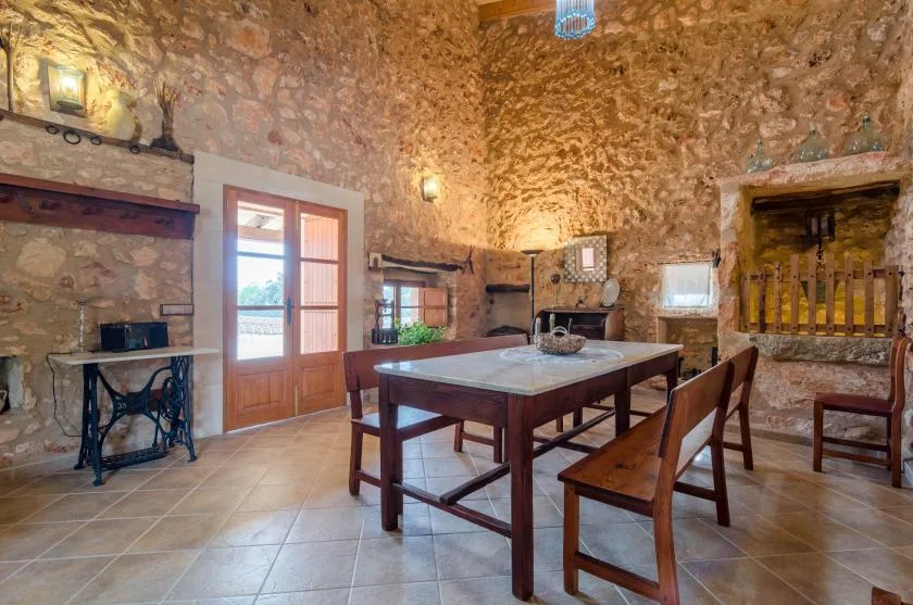 A stone-walled dining room has a wooden table and chairs.