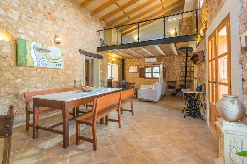 A rustic stone interior with a dining table and seating beneath a loft.