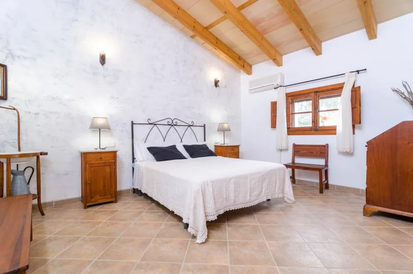 A bedroom with a double bed beneath exposed wooden ceiling beams.