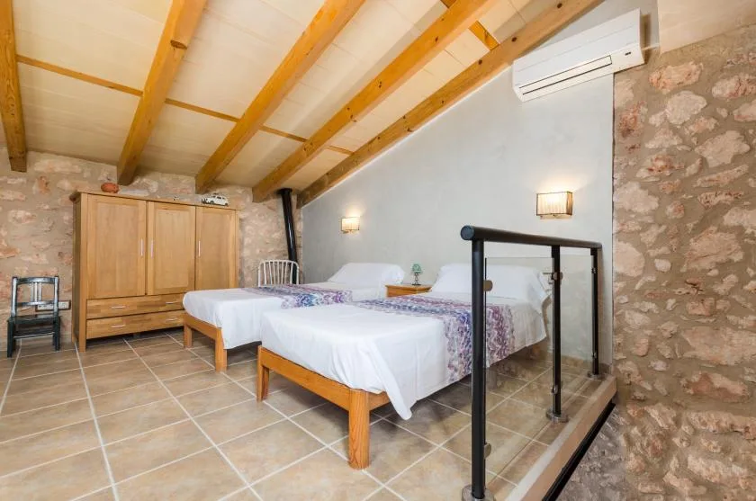 A bedroom with several beds, a wooden wardrobe, and exposed ceiling beams.