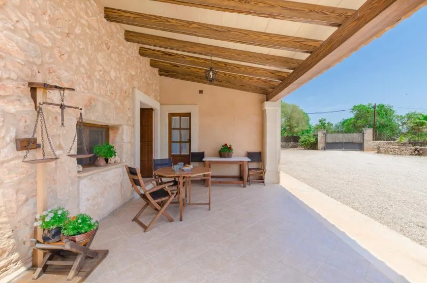 A covered outdoor patio with a dining table and stone wall.