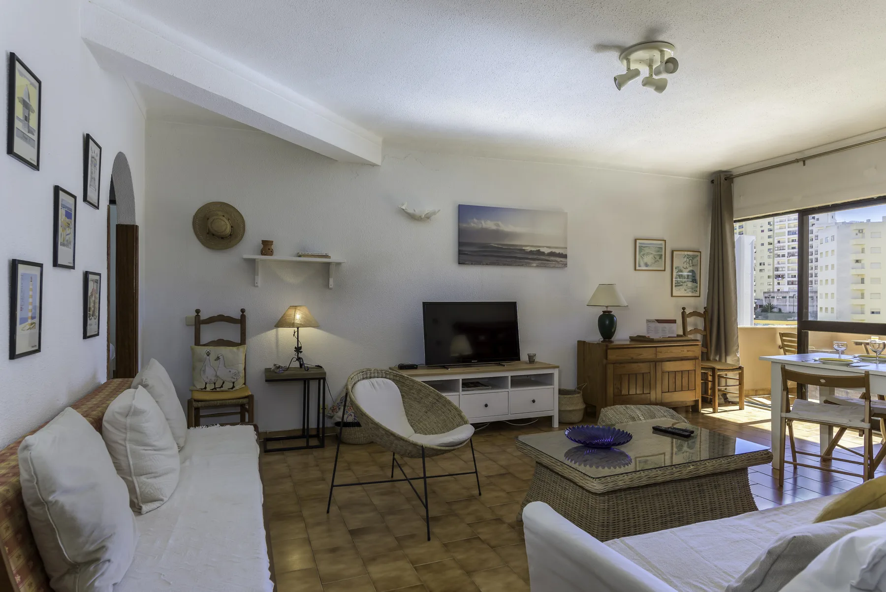 Living room with seating, a television, and a dining area by the windows.