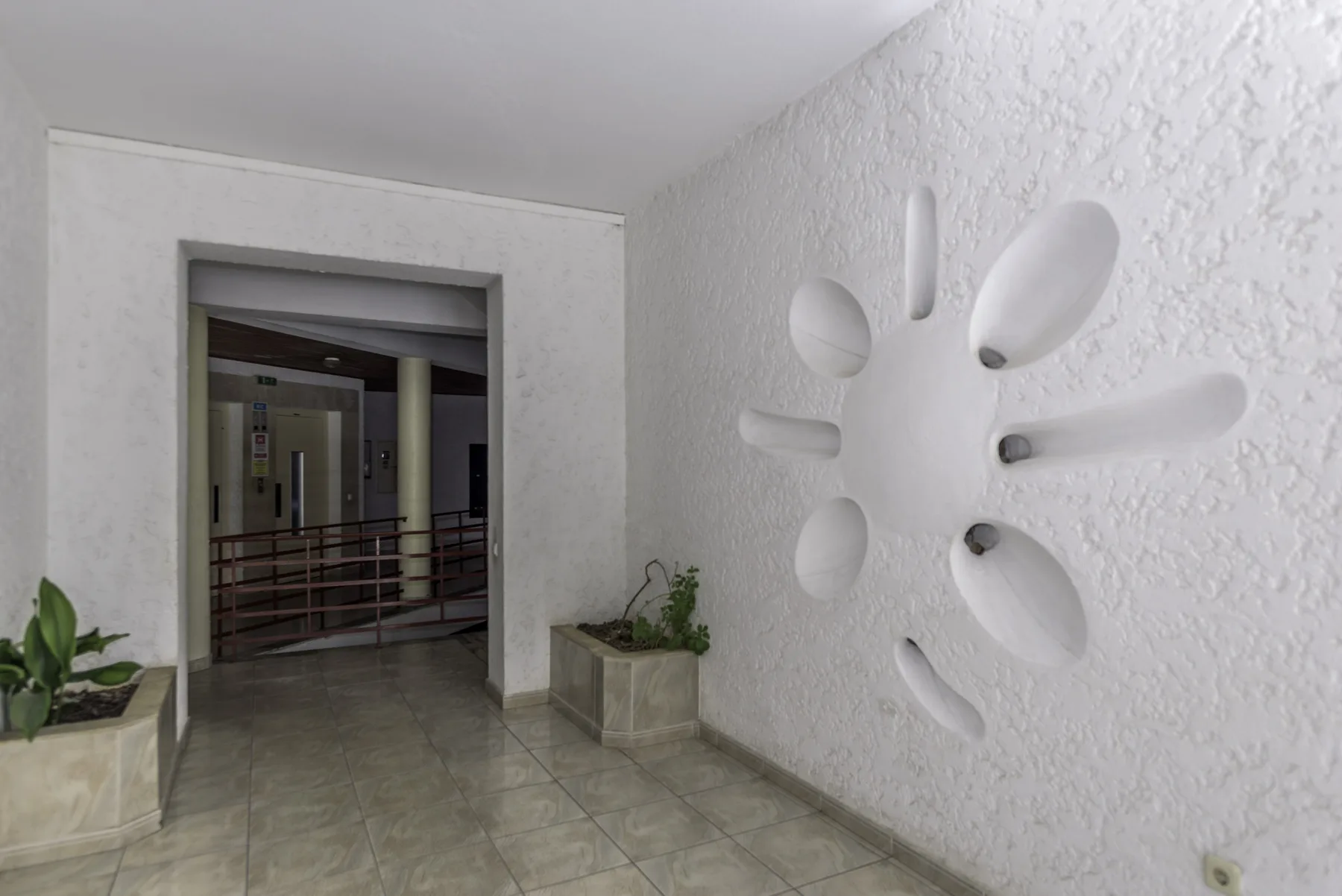 A bright entry hall with a large white sculptural wall decoration.