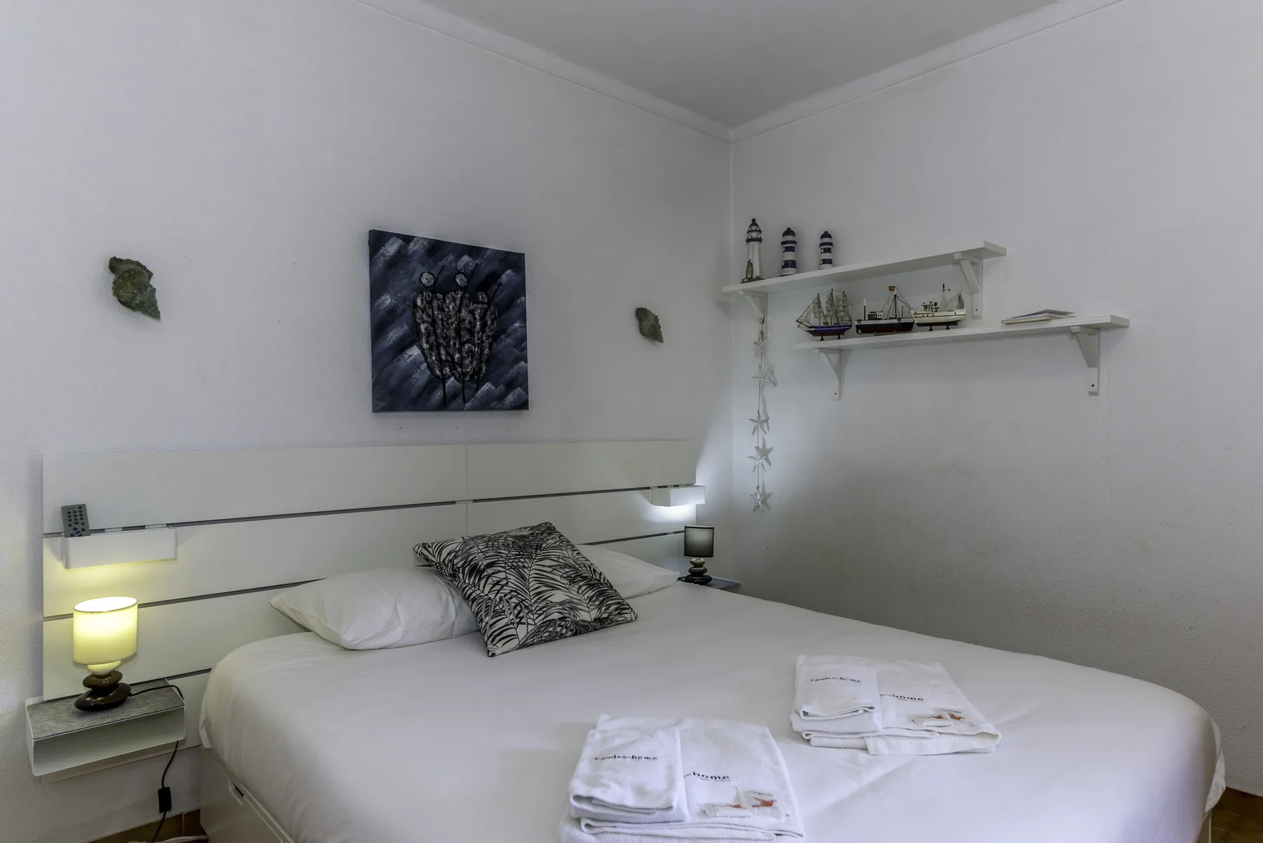 A bedroom with a neatly made bed and decorative wall art.