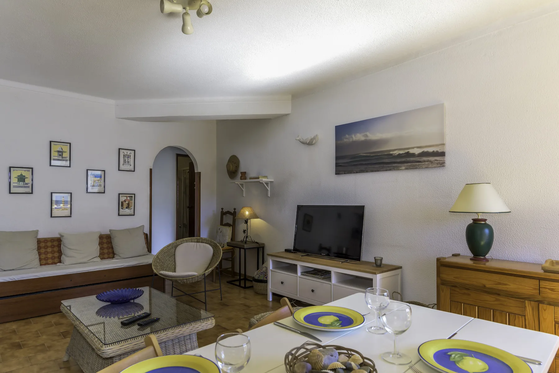 A living and dining room with a television and table set for a meal.