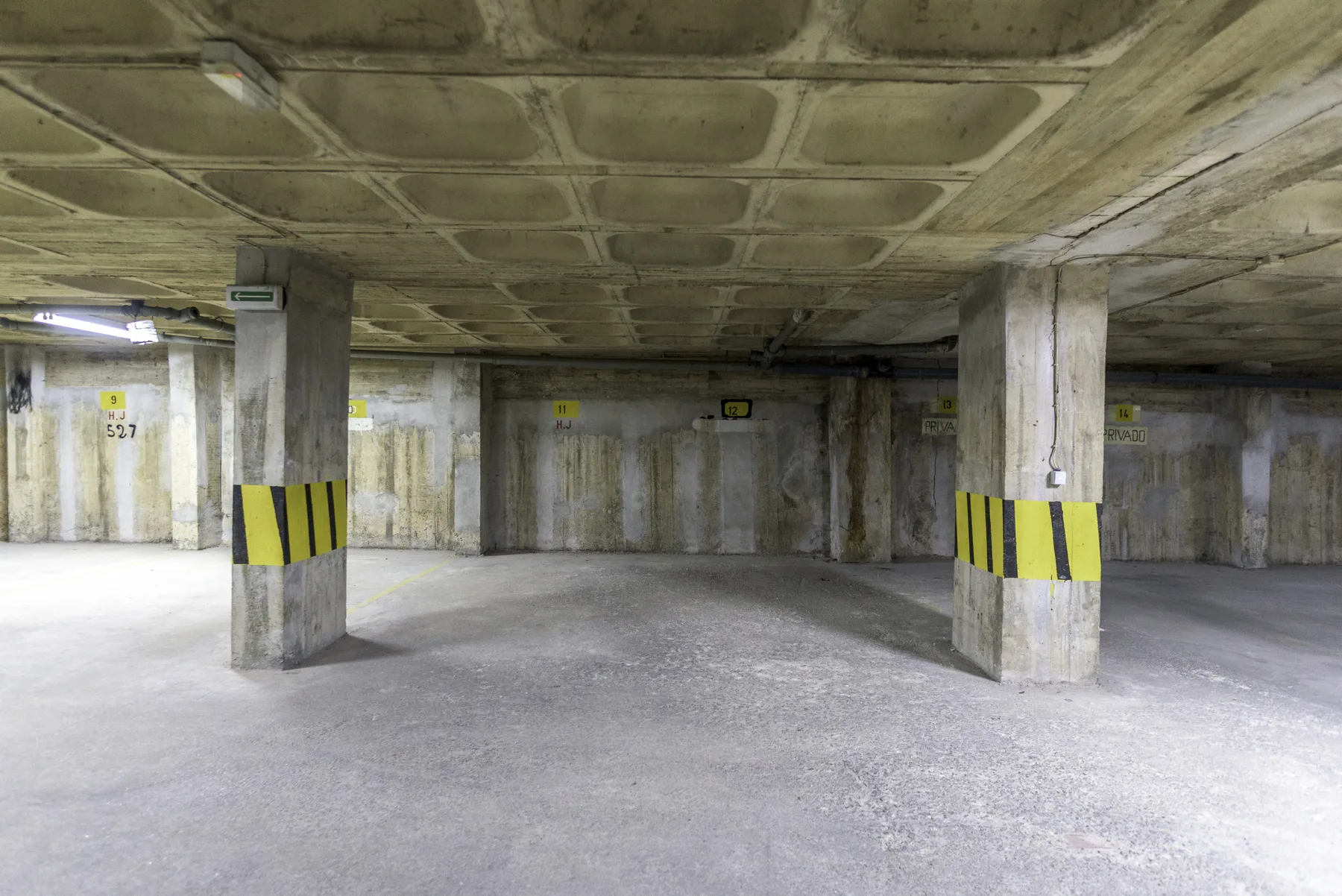 An underground parking garage with concrete pillars and yellow-and-black markings.