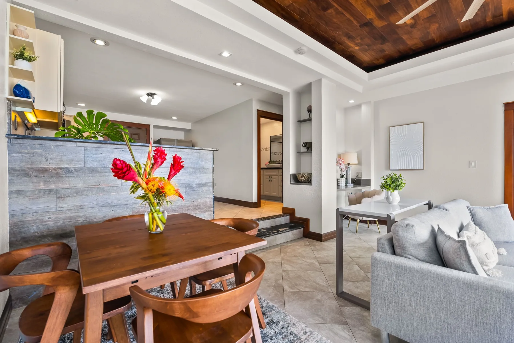 A dining and living area with a wooden table, seating, and an open kitchen.