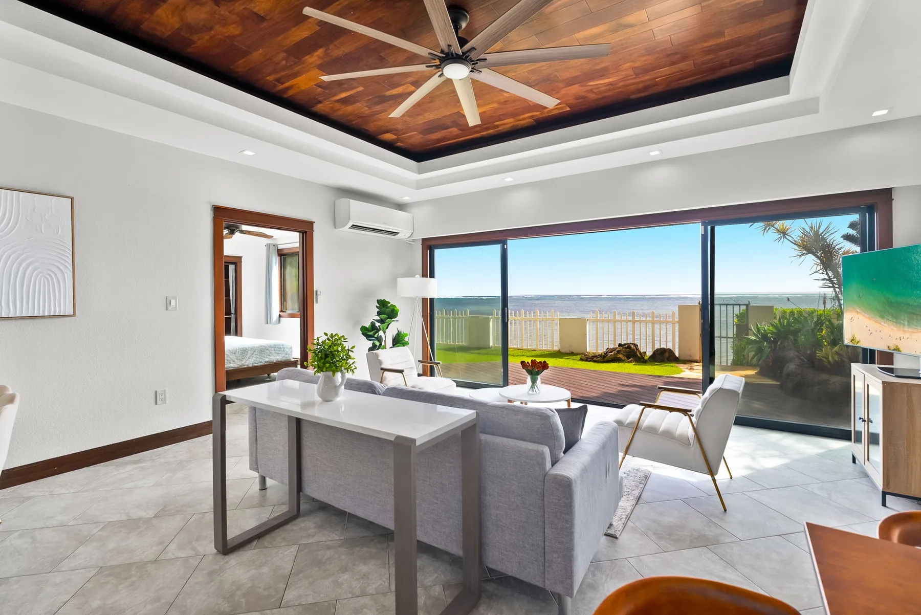 A bright living room with seating, a ceiling fan, and wide sliding glass doors.