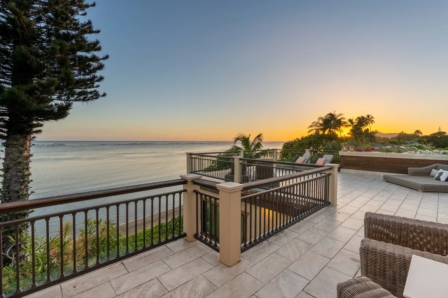 A tiled seaside terrace overlooks the water at sunset.
