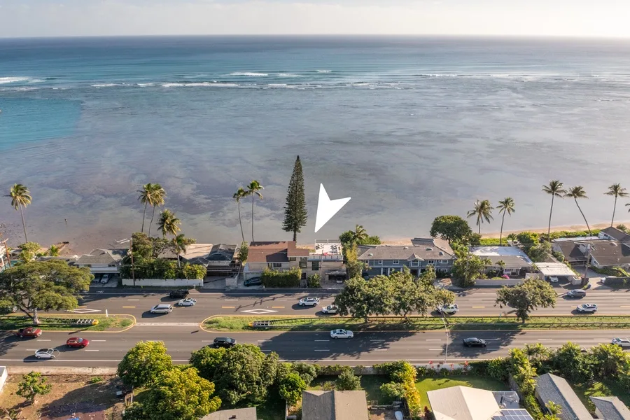 Aerial view of a coastal road and buildings beside the ocean.