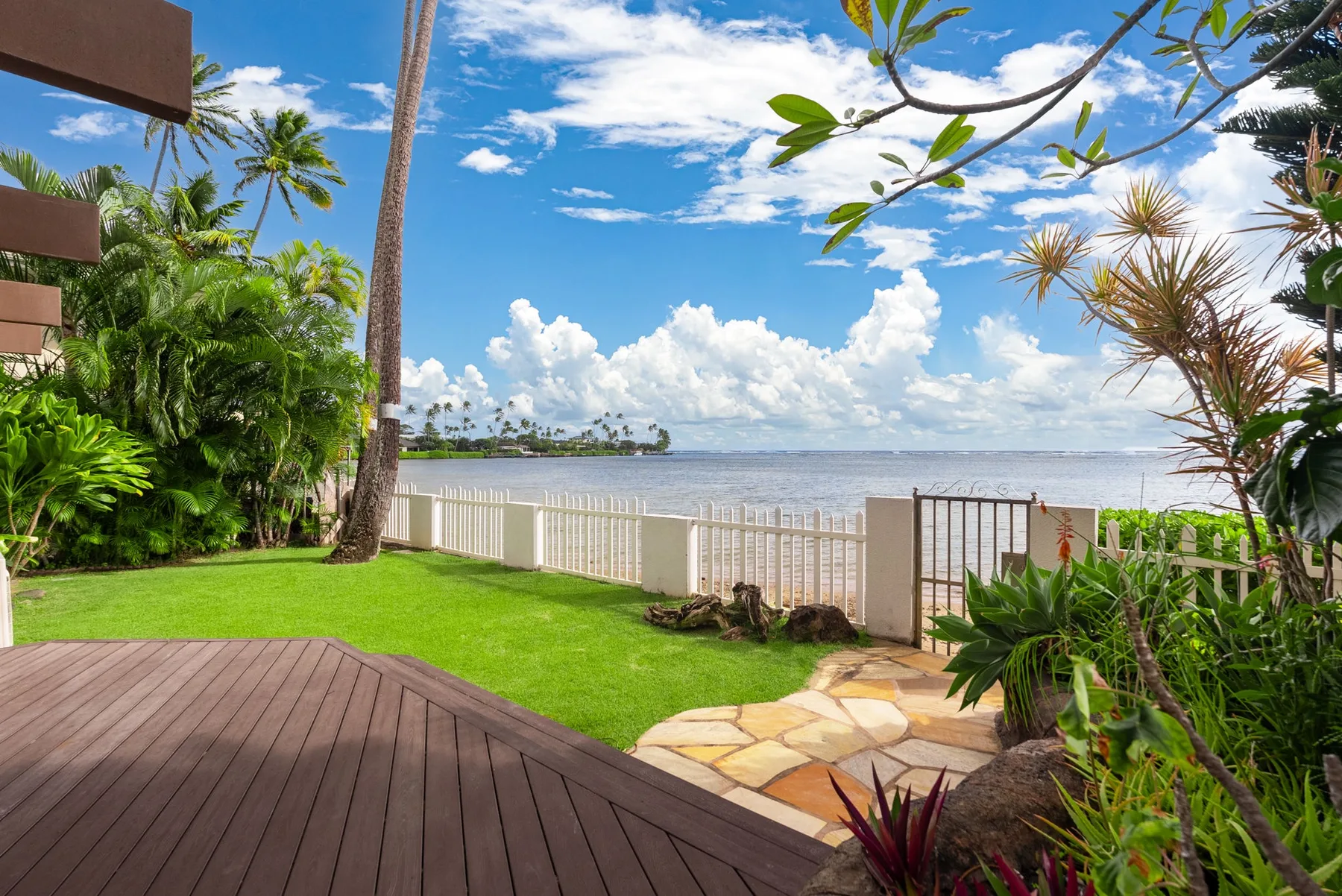 A landscaped waterfront patio opens onto a calm body of water.