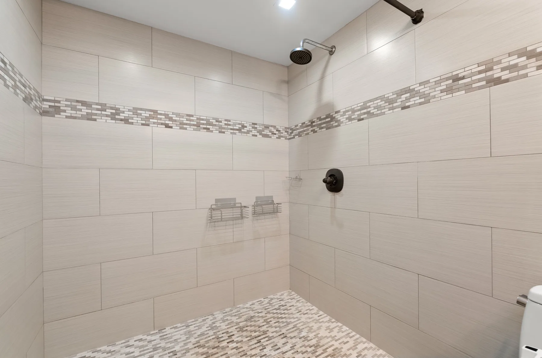 A tiled shower area with a handheld showerhead and patterned floor.