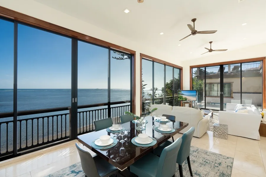 A bright dining and living area overlooks the ocean through large windows.