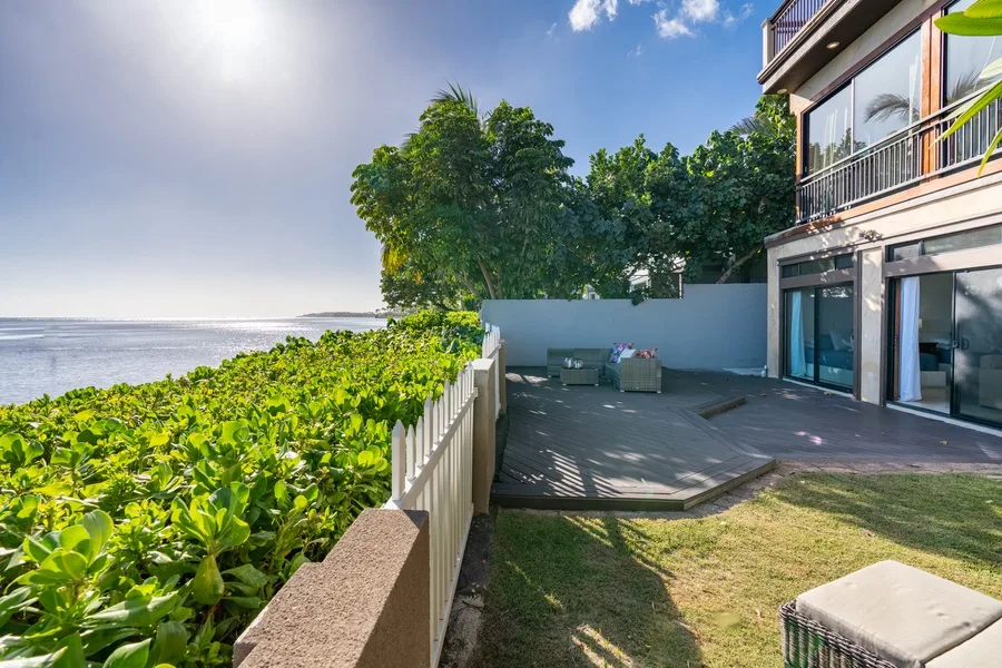 An outdoor patio beside a modern building overlooks the ocean.