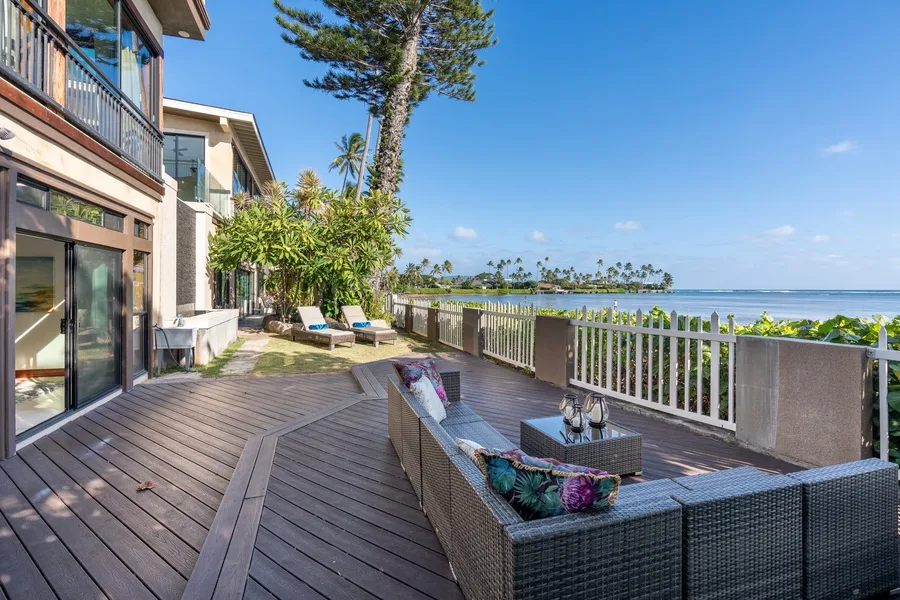 A seaside deck has outdoor seating and a view of the ocean.