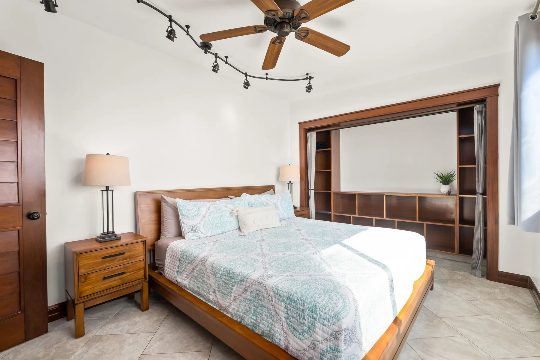 A bedroom with a bed, wooden bedside table, and built-in shelving.