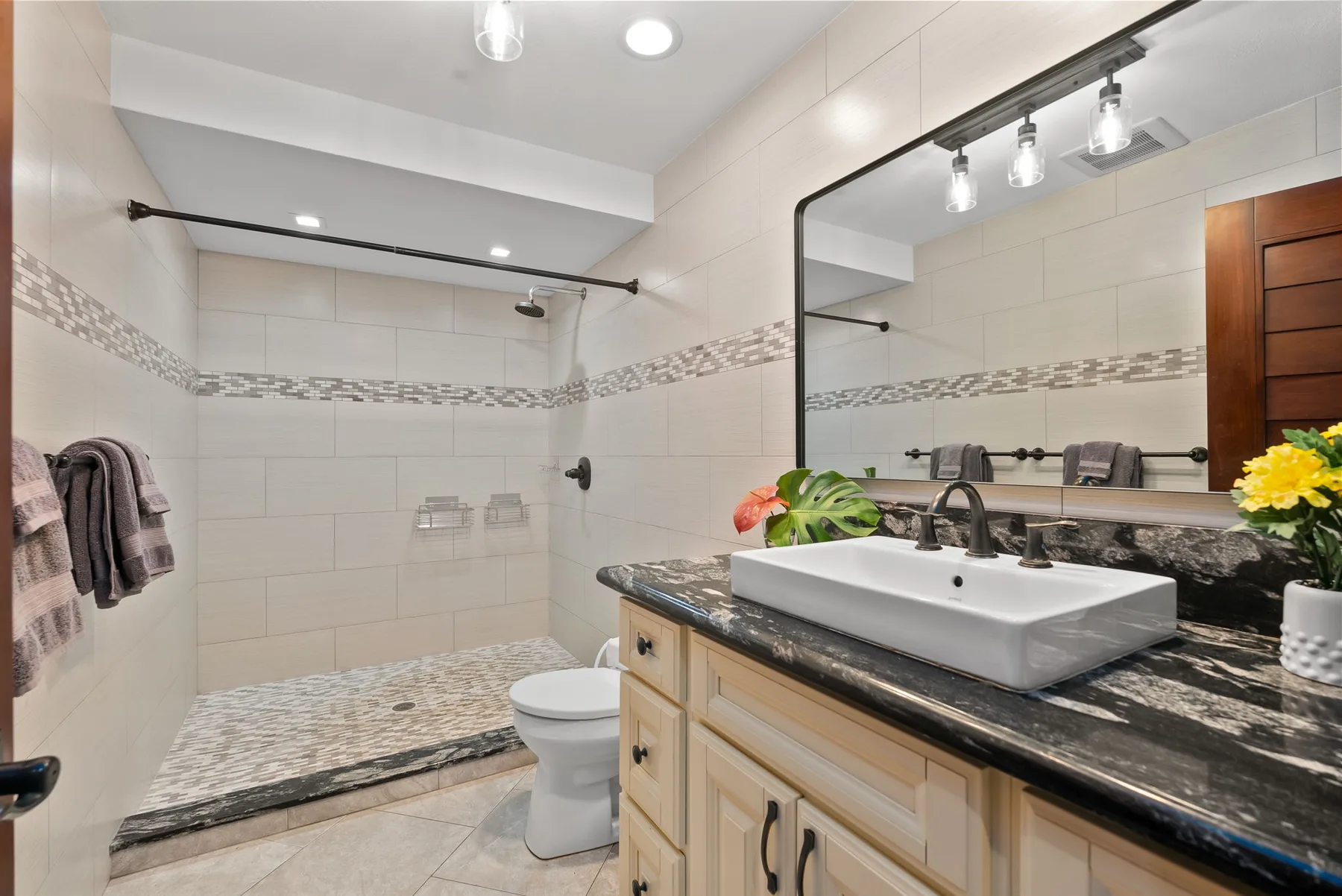A tiled bathroom with a walk-in shower and a vanity topped by a sink.