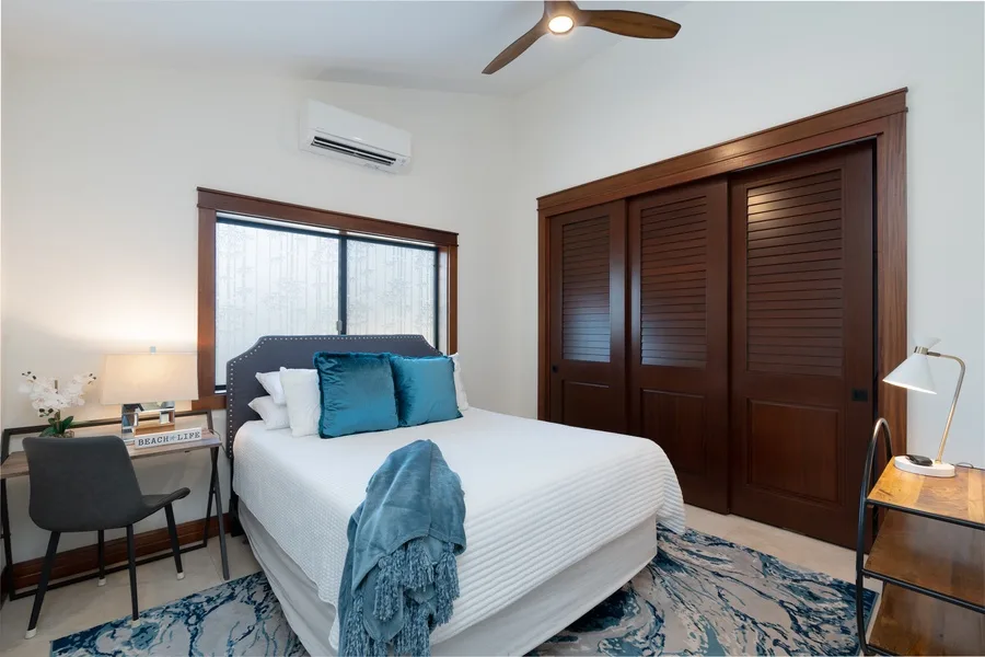 A bedroom with a bed, dark wood closet doors, and a window.