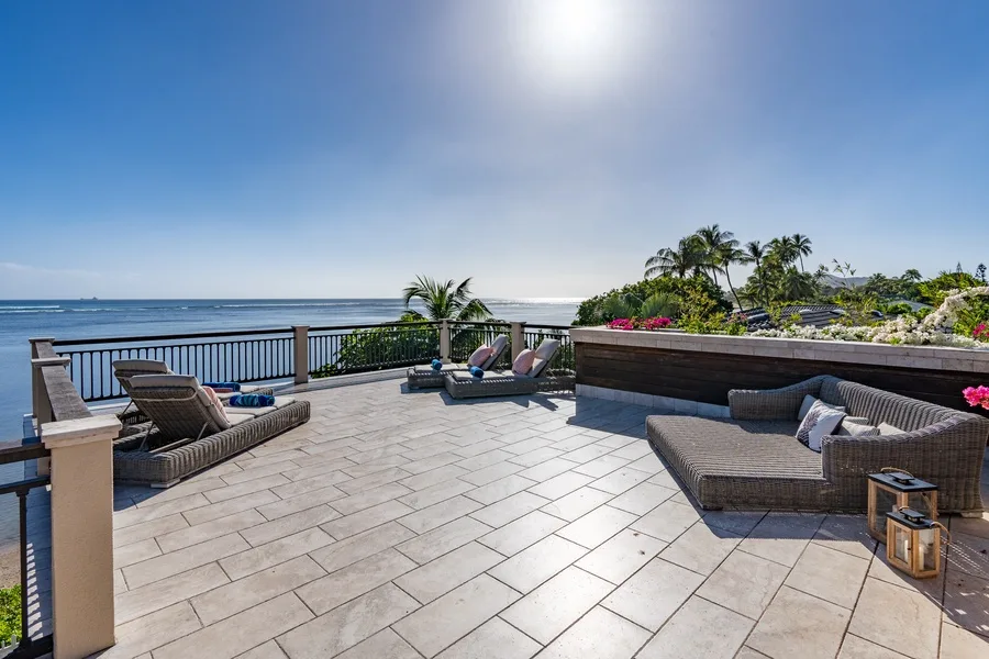 A sunlit patio with lounge seating overlooks the ocean.