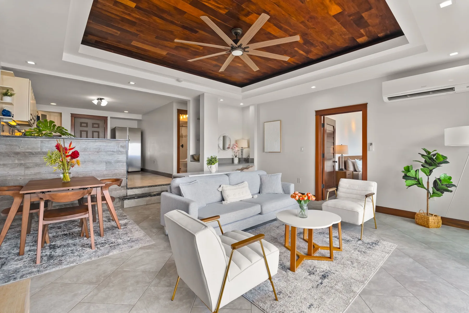 A bright living room with a gray sofa, seating, and a dining area.
