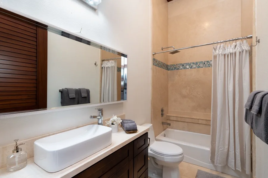 A bathroom with a sink, toilet, and bathtub behind a shower curtain.