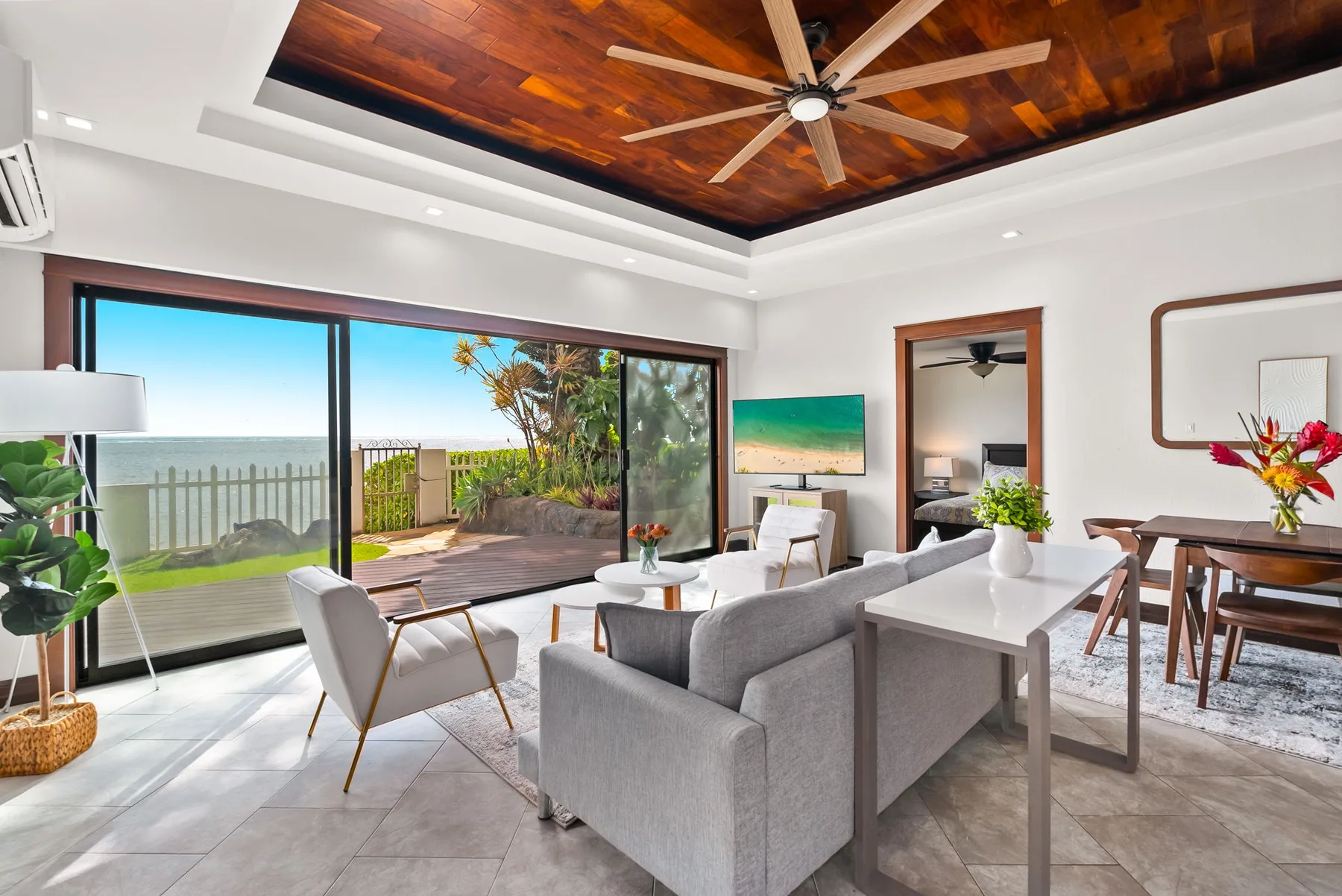 A bright living and dining area opens onto a patio with ocean views.