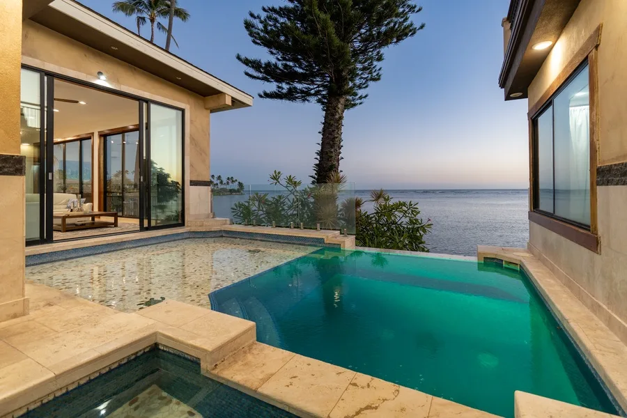 A seaside pool beside a modern building, with the ocean visible beyond.